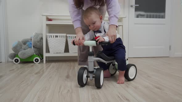 Mother and Baby Boy Play on the Floor Mother Teaches 1 Year Old Child to Ride a Balance Bike