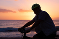 Silhouette of mature man riding his bicycle at the beach at sunset. Horizon over water - PhotoDune Item for Sale