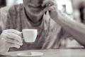 Cropped shot of defocused senior man talking on mobile phone while drinking coffee at cafeteria - PhotoDune Item for Sale