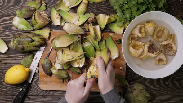 Woman Cleaning Artichokes with Knife