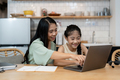 Mother teaching children to do their homework at home. Happy asian family using the laptop together - PhotoDune Item for Sale