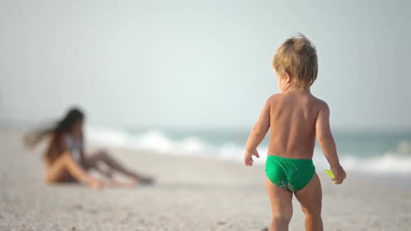 Older Sister Playing with Younger Brother Aground Near the Shore on Summer Vacation