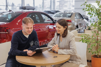person and car rental helps with the purchase. signing a trade-in contract and handing over keys, shaking hands. A successful man chooses a new car