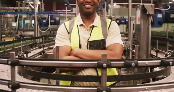 Portrait of worker standing with arms crossed near production line