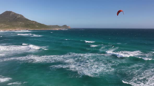 Kitesurfer in huge air off wave with pointed Cape of good hope in backdrop; drone