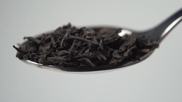 A full teaspoon of dried Chinese black tea leaves. Falling in slow motion.