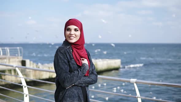 Young Muslim Girl Enjoys Walking Near the Seaside with Seagulls Flying on the Background alt