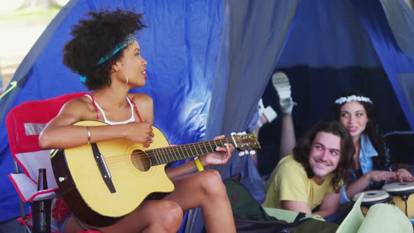 Woman playing guitar for her friends at a music festival 4k