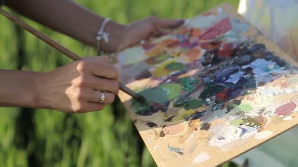 Girl artist paints a picture with oil paints.