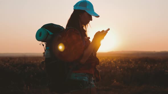 Silhouette of Young Tourist Woman Use Phone with Dramatic Sunset Sky Background. Always Connected