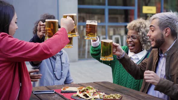 Group of Happy Friends Toasting with Beer While Having Lunch Outdoors