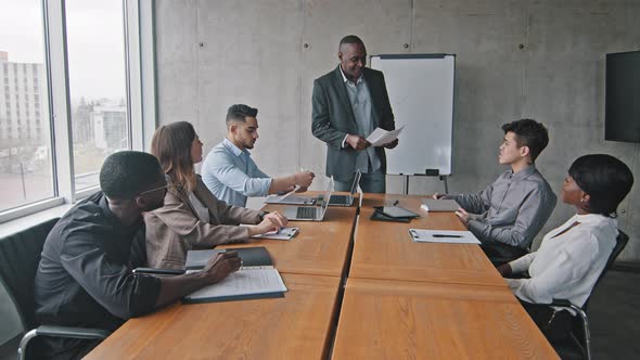 African Mature Male Boss Mentor Leader Coach Standing in Office Boardroom Giving Colleagues