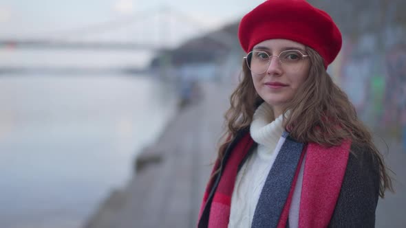 Young Charming Woman in Red Beret and Eyeglasses Admiring Beauty of Nature Standing on Urban