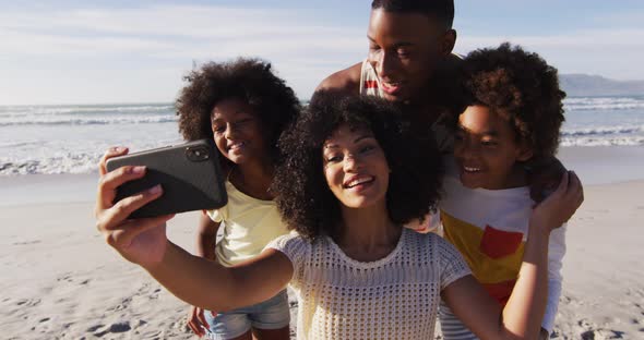 African american parents and their children taking a selfie with smartphone on the beach