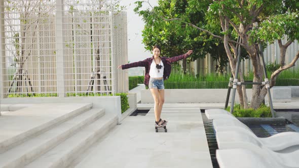 Attractive Asian woman smiling  play skateboard outdoor