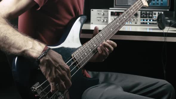 Musician records a bass guitar track in his own studio.