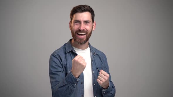 Portrait of happy screaming handsome bearded young man standing with surprised face