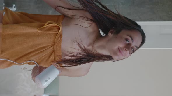 Young Beautiful Woman Standing in Front of the Mirror and Using Hairdryer While Drying Hair After