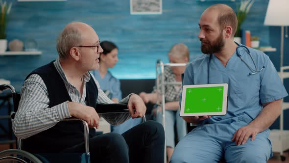 Man Nurse and Old Patient Looking at Green Screen on Tablet