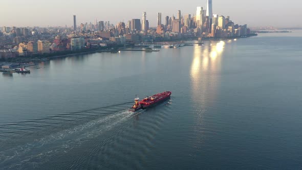 An aerial view of lower Manhattan and New Jersey from over the Hudson River at sunrise. The sun refl