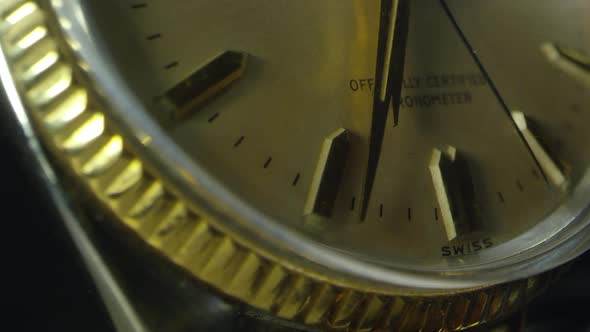 Macro of watch as second hand ticks past minute and hour hands