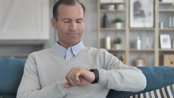 Middle Aged Man Relaxing on Couch and Using Smartwatch Applications