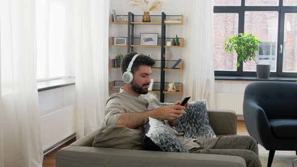 Man in Headphones Listening To Music on Smartphone