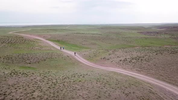 A Group of Cyclists Ride on the Green Steppe
