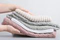 female hands holding a pile pastel color jumpers and other knitted clothing. - PhotoDune Item for Sale