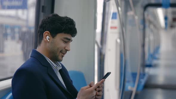 Side View of Man in Wireless Earphones Using Mobile in Metro
