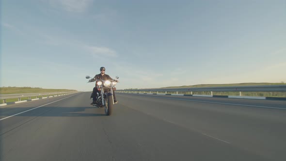 Man in Helmet and Sunglasses Rides Motorbike on Road Front View