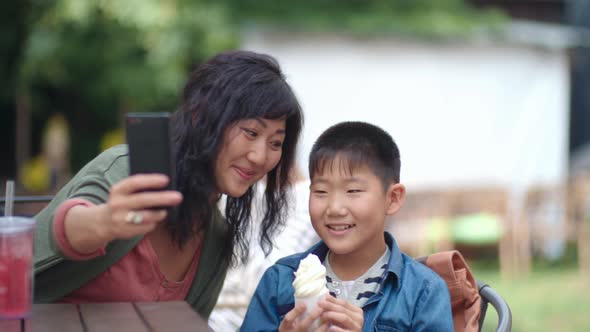 Mom and Child Taking Picture with Smartphone in Cafe Outdoors