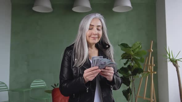 Rich Fashion 60-Aged Woman with Long Gray Hair which Counting Dollars Banknotes