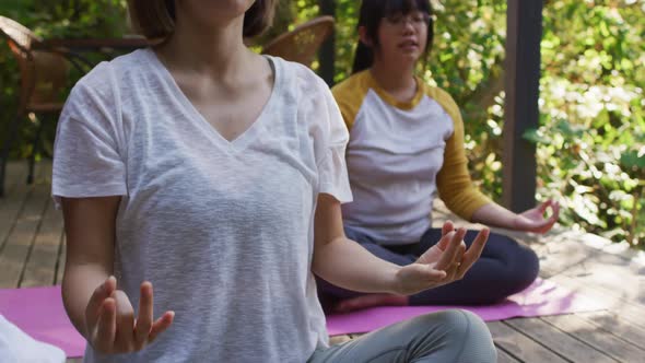 Asian mother and daughter meditating together in garden