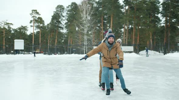 Happy Youth Girls and Guys Ice-skating at Frozen Lake in Park Having Fun Laughing