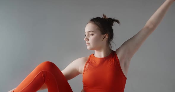 Young Pretty Woman Stands in Red Training Form and Lift Her Leg To Her Head, Dancer Demonstrates Her