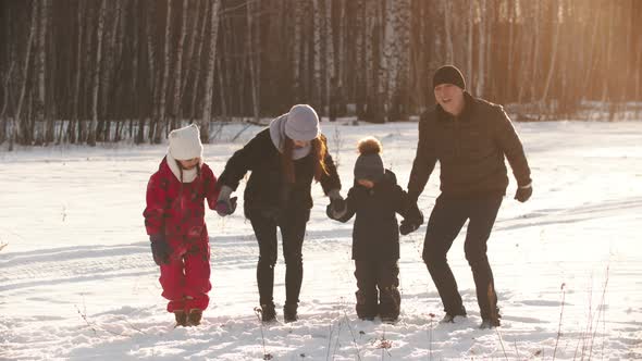 A Young Happy Family Holding Hands and Jumping - Winter