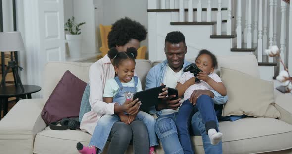 African American Family at Home while Revisioning Funny Videos on Tablet PC