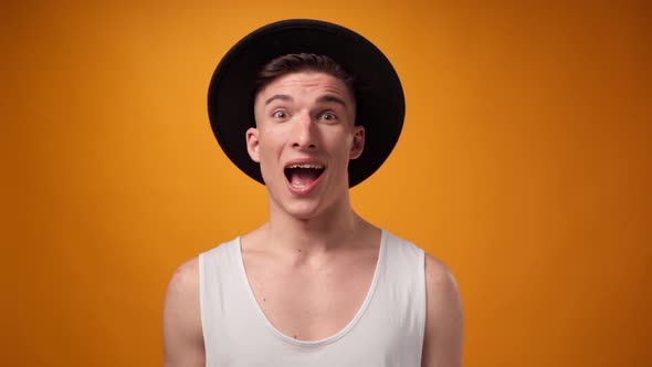 Surprised Young Man Standing Against Yellow Background in Studio