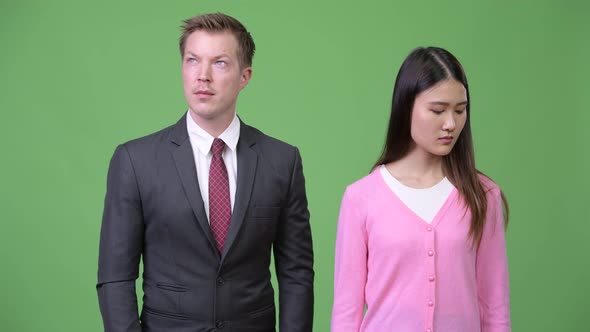 Young Sad Asian Woman and Young Happy Businessman Thinking Together
