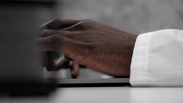 Close Up Hands African American Man Doctor Typing on Keyboard Laptop in Clinic