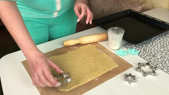 A Woman Squeezes Cookies Out Of Rolled Out Dough.