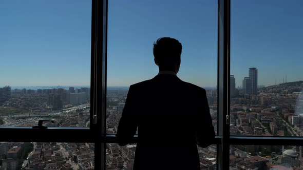 Successful Businessman Is Looking at Panoramic City View From His Modern Apartment.