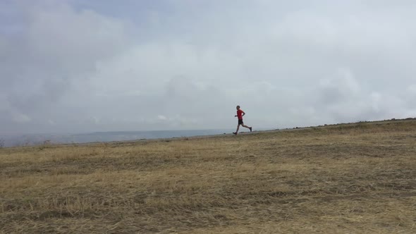 Cinematic aerial view of a sport man running on a countryside road