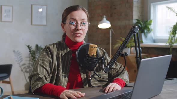 Cheerful Female Vlogger Speaking at Camera in Recording Studio