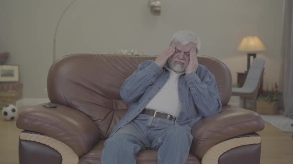 Attentive Adult Son Bringing Pills and Water To Senior Father Having Headache. Young Caucasian Man