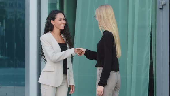 Friendly Smiling Millennial Diverse Female Colleagues Greeting Each Other By Handshaking