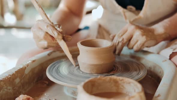 Female Potter Sitting and Makes a Cup on the Pottery Wheel. Woman Making Ceramic Item. Pottery