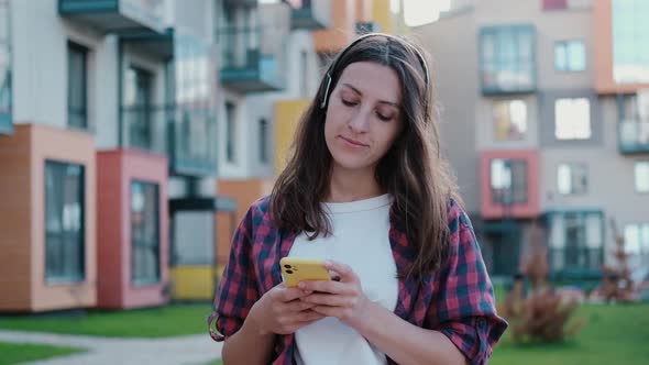 Attractive Girl Looks at Smartphone Checking Social Networks Outdoors