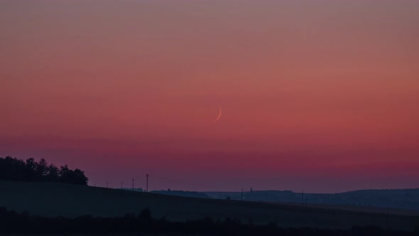 Crescent moon set time lapse with orange sky and short fireworks on the horizon, framing following t